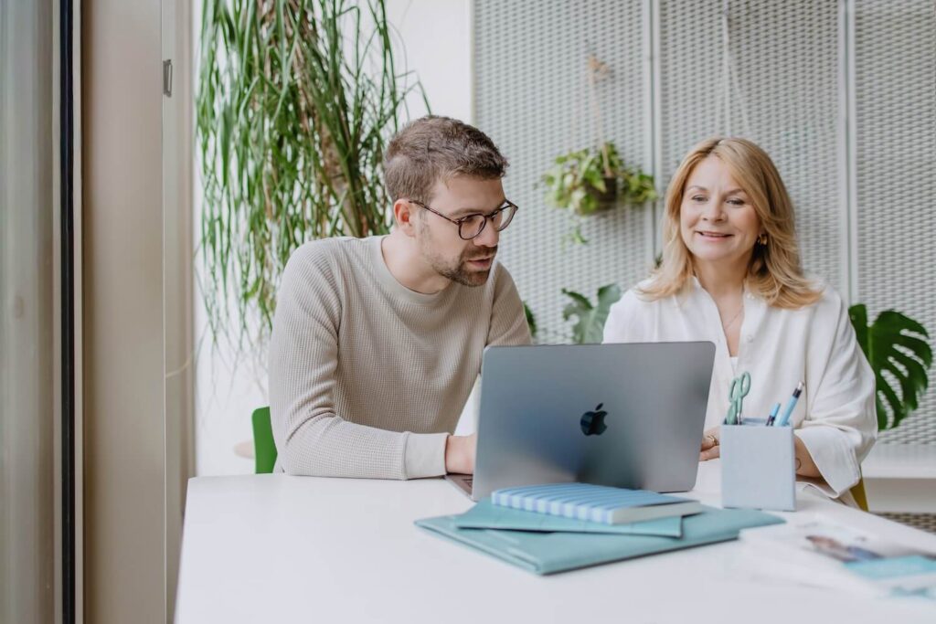Ein Mann und eine Frau unterhalten sich während sie auf einen Laptop schauen