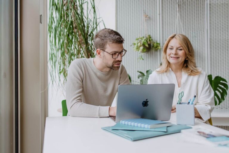 Ein Mann und eine Frau unterhalten sich während sie auf einen Laptop schauen